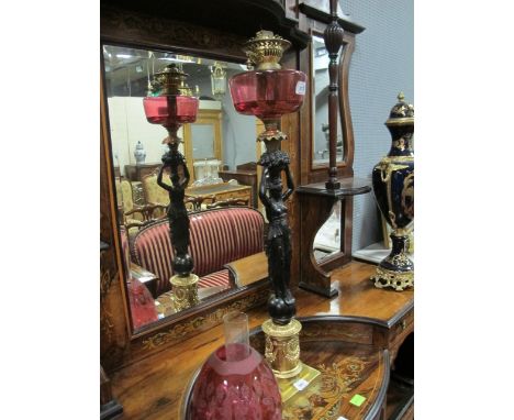 A FINE GILT BRASS FIGURAL OIL LAMP with ruby etched glass shade and reservoir raised on a cylindrical base moulded in relief 