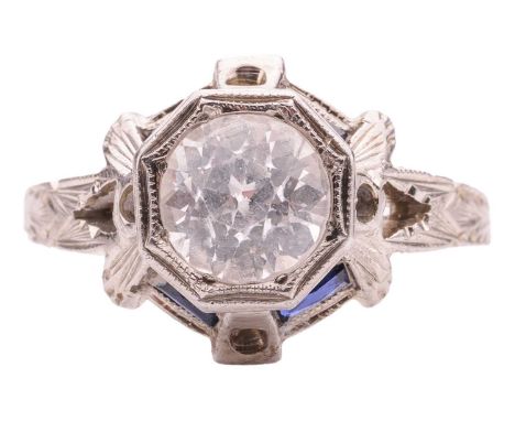 An Art Deco-style ring set with sapphires; centred with a circular-cut white sapphire of 6.5 x 4.5 mm, in a raised octagonal 