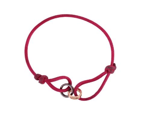 Cartier - a 'Love Charity' bracelet, featuring two interlocking Love rings, one in 18ct rose gold with four diamond accents, 