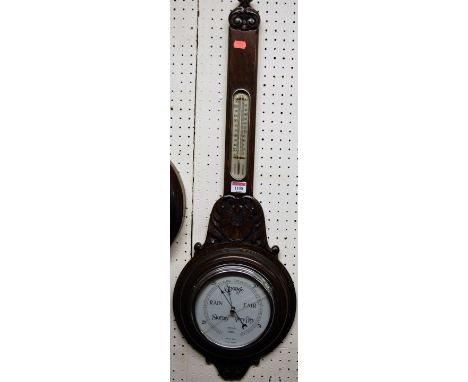 A 1930s relief carved oak two dial aneroid wheel barometer