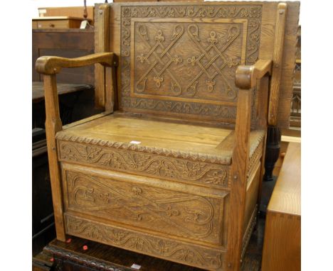 An early 20th century line and relief carved oak single fold-over monks bench, having hinged box seat base and hammered coppe