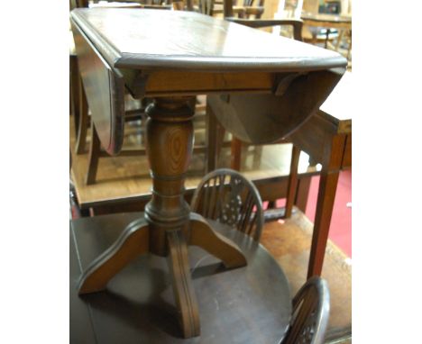 A contemporary Ercol dark elm dropflap pedestal supper table; together with a pair of dark elm elbow chairs (3)