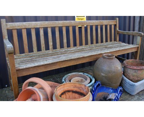 A contemporary stained and slatted teak three-seater garden bench, w.182cm