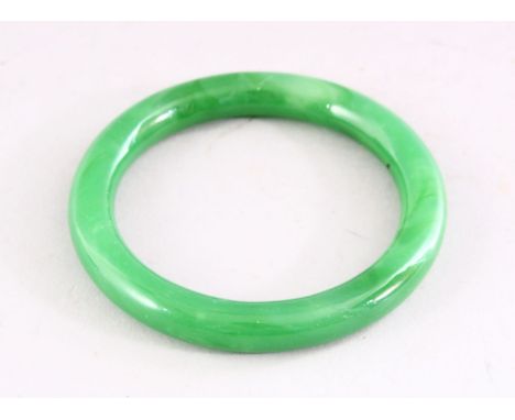 A CHINESE GREEN JADE BANGLE, 8.5cm diameter.
