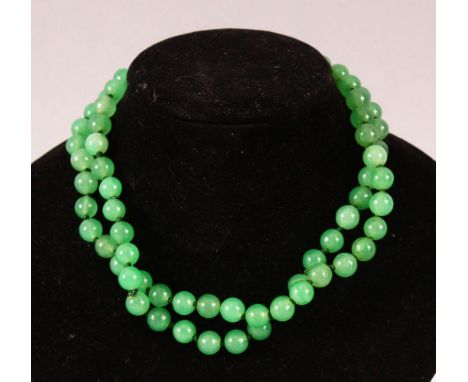 A STRING OF JADE BEADS, 66cm long.
