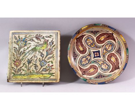 AN ISLAMIC GLAZED TILE, painted with a bird and flowers, 24.5cm x 24.5cm. together with an Eastern pottery circular bowl with