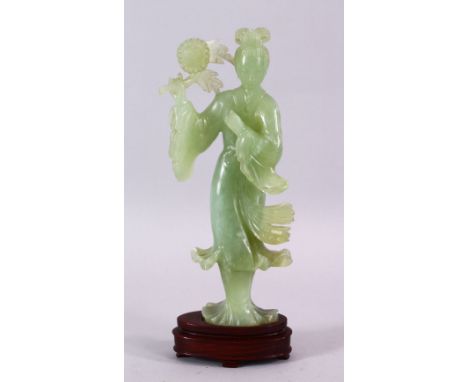 A CHINESE CARVED JADE FIGURE OF GUANYIN, stood holding a bouquet above her head, on a wooden stand, 24cm high.