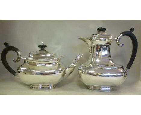 A silver teapot of bulbous form with a serpentine outlined rim, an ebonised handle and knop to the hinged lid and a matching 