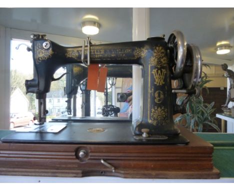 A Wheeler & Wilson D9 manual sewing machine, circa 1895, decorated in gilding on black, hinged on a rectangular mahogany box 