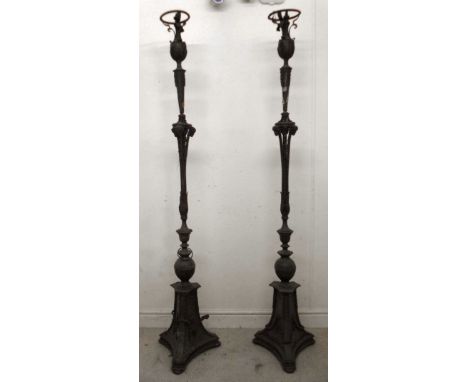 A pair of early 20thC brass standard lamps with cast and applied foliate, swag and rams' mask ornament, each having a knopped