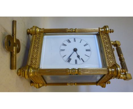 A mid 20thC lacquered brass cased carriage clock, having bevelled glass panels, cast blind filigree worked frieze panels, flu