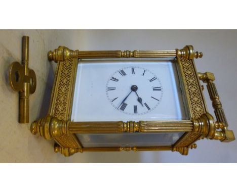 A mid 20thC lacquered brass cased carriage clock, having bevelled glass panels, cast blind filigree worked frieze panels, flu