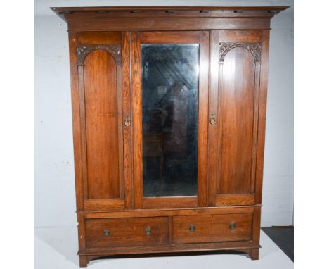 Early 20th century oak triple wardrobe, rectangular bevelled mirror to centre panel, flanked by panelled doors, above two dee