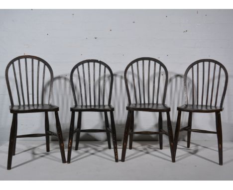 Four stained wood stick back kitchen chairs.