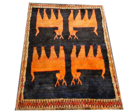 A Gabbeh rug, with four orange deer against a deep navy ground, enclosed by diamond borders, 132 x 101cm.