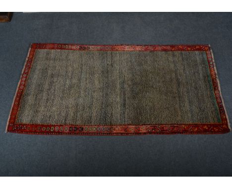 Gabbeh wool rug; a speckled field, enclosed by red borders with boteh floral emblems, 202 x 107cm.