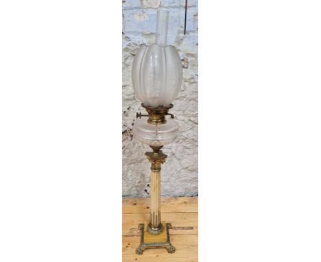 A large oil lamp with clear glass resevoir and corinthian column,  Height 86cm.Condition:- General wear through age and use, 