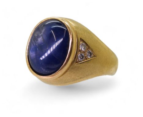 A bright yellow metal ring set with a large opaque sapphire set with estimated approx 0.18cts of brilliant cut diamonds acros