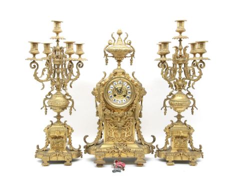 An early 20th Century gilt metal clock garniture, the clock with an urn finial over a body decorated with floral swags, 'C' s