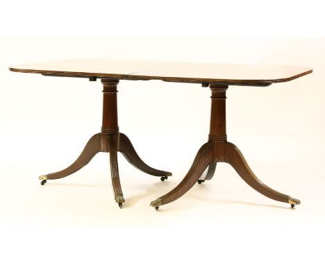 A Regency design twin pillar mahogany dining table, with two extra leaves, the reeded top on twin tripod supports, total leng