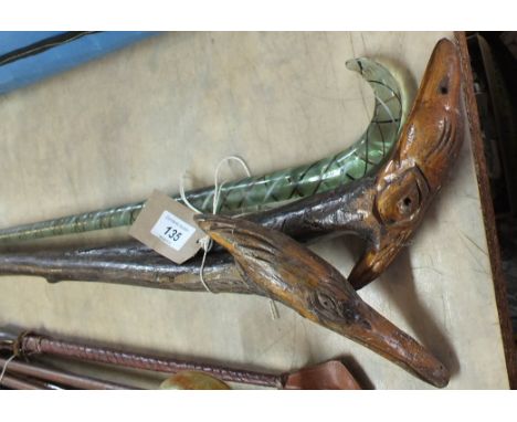 A Nailsea glass walking stick with coloured spiral decoration plus two wooden sticks with birds head grips