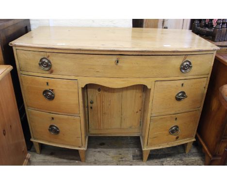 An early 19th Century bow front pine kneehole desk with five drawers on tapered feet