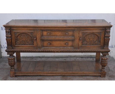 A 19th Century oak sideboard, two drawers to centre flanked by two foliate carved doors, pot shelf below, raised on oversized