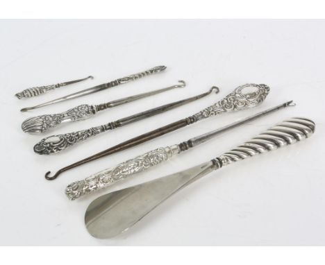 Seven silver handled tools including a shoe horn, and button hooks, varied designs and date