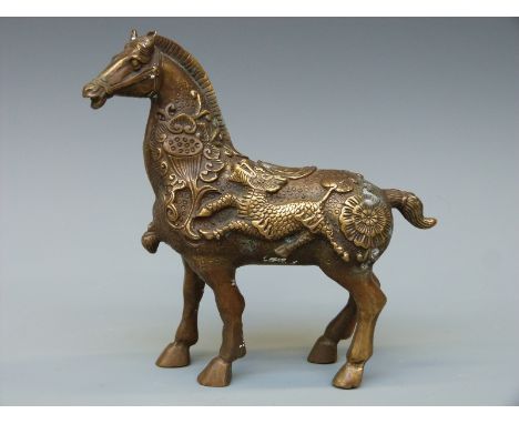 A Japanese brass or bronze figure of a horse with relief decoration of mythical beasts,16cm tall