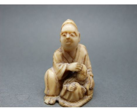 A Japanese Meiji period ivory netsuke of a man with child, 3.8cm tall