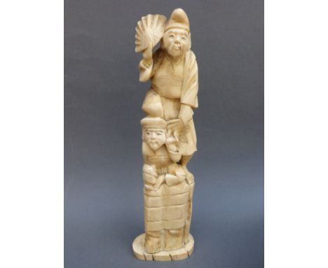 A Japanese Meiji period okimono of two figures atop a boulder, 24cm tall