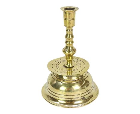 A German Brass Nuremberg candlestick. Late 17th century, with a baluster turned stem above a broad drip pan and bell form bas