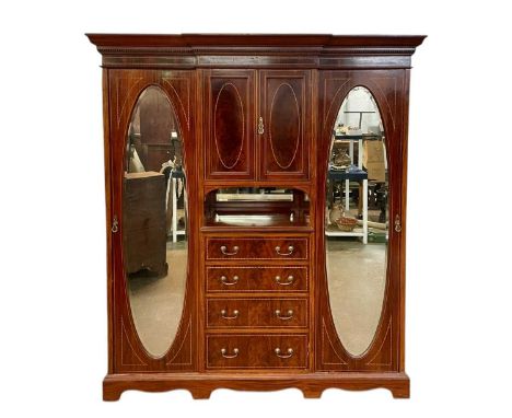 An Edwardian mahogany inlaid triple wardrobe. Featuring boxwood and ebony inlay, four drawers under a cupboard to the centre,
