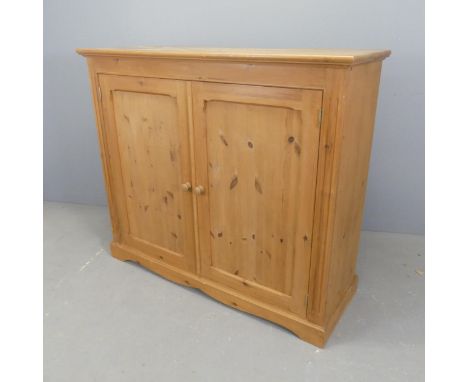 A modern pine hall cabinet, with two panelled doors and shelf fitted interior. W126cm, H109cm, D44cm.