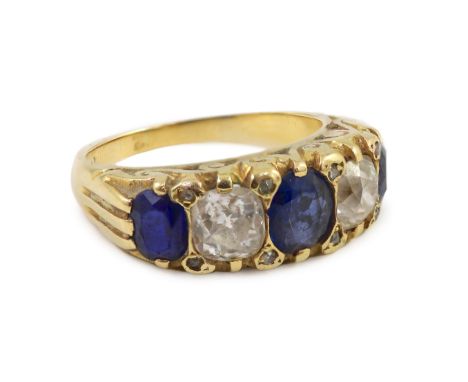 An early 20th century 18ct gold, three stone sapphire and two stone diamond set half hoop ring, with carved setting and diamo