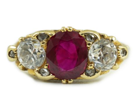 A Victorian style 18ct gold single stone oval cut ruby and two stone round cut diamond set ring, with carved setting and diam