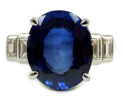 A platinum and single stone oval cut sapphire set cocktail ring, with graduated four stone baguette cut diamond set shoulders