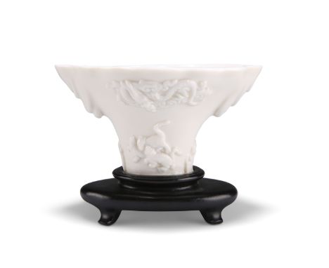 A CHINESE BLANC DE CHINE LIBATION CUP, KANGXI PERIOD, decorated to each side with kylins beneath a dragon in the clouds, on a