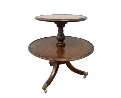 A Regency mahogany two tier dumb waiter with moulded edges   on turned supports and downswept tripod base terminating in bras