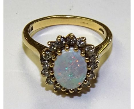 An 18ct gold opal and diamond ring, the central oval cabochon opal, mounted by 16 brilliant cut diamonds, measuring approxima