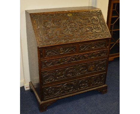 A Jacobean style carved oak writing bureau circa late 19th century, with fall front enclosing drawers and pigeon holes, above