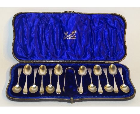 A cased set of 12 silver teaspoons with sugar tongs, hallmarks for London 1909 Wakely & Wheeler, of plain design with monogra