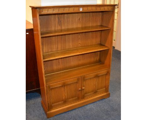 An Ercol open bookcase, with open shelving above two cupboard doors, 138cm high x 101cm wide x 30cm deep