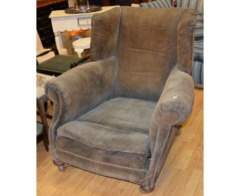 A large vintage wing back armchair circa early 20th century, upholstered in cord fabric, raised on bun feet, 101cm high
