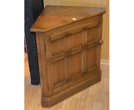 An Ercol Windsor style corner cupboard, with panelled door enclosing shelved interior, 71cm high x 68cm wide x 40cm deep