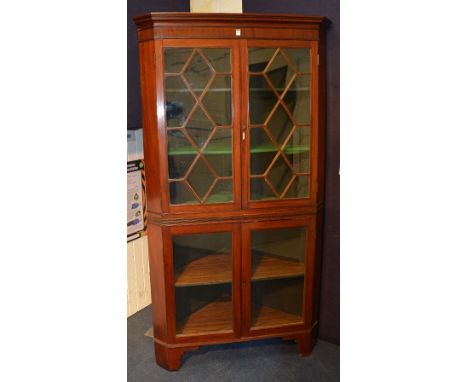 A 19th century mahogany corner cabinet on base, with moulded cornice above two glazed astragal doors, enclosing shelved inter