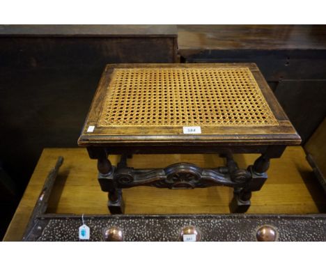 A Jacobean style carved and pierced solid oak stool, with cane work seat, circa 1920. 