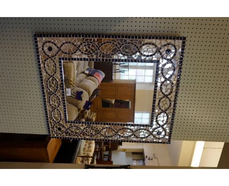 A decorative contemporary wall mirror, decorated with glazed ceramic mosaic borders.