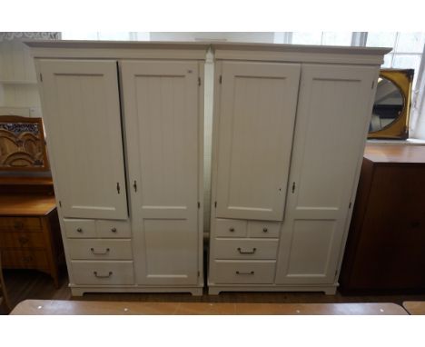 A pair of stylish contemporary white finished wardrobes, each having one slatted full length door, flanked by a half length d