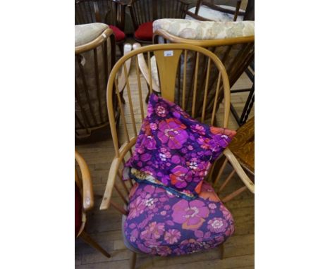 An Ercol light elm comb back Windsor chair, with psychedelic upholstered loose seat and back cushions.